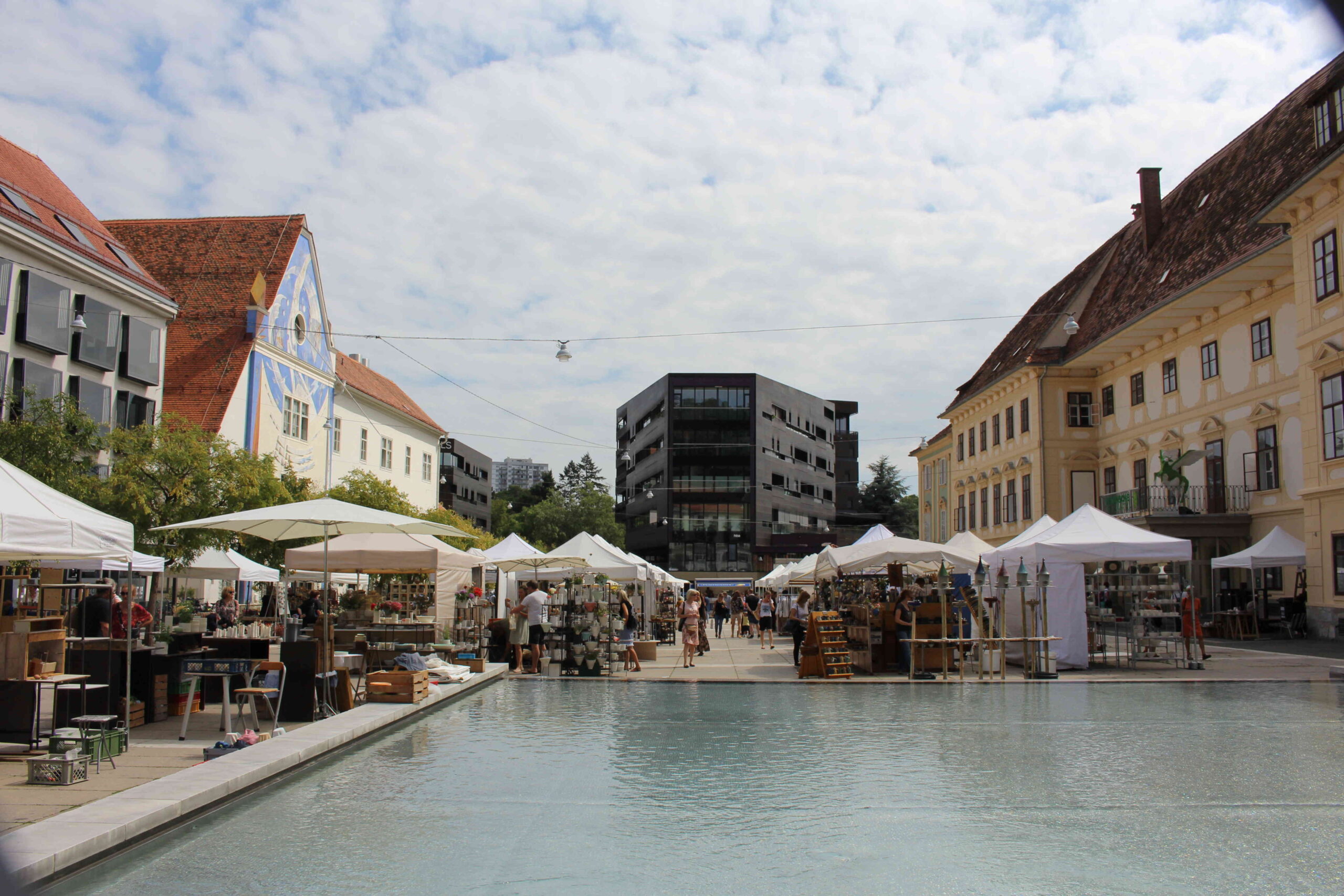 Marktstände rund um den Brunnen am Karmeliterplatz in Graz.